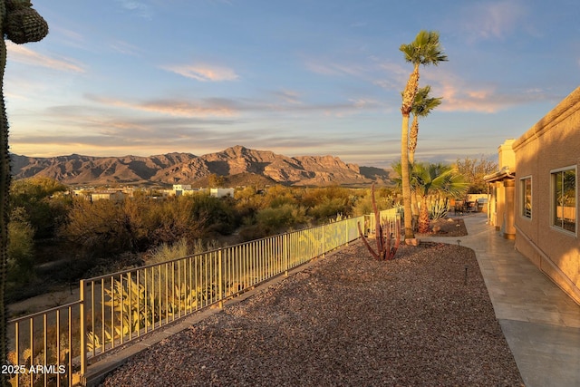 yard at dusk featuring a patio, a fenced backyard, and a mountain view