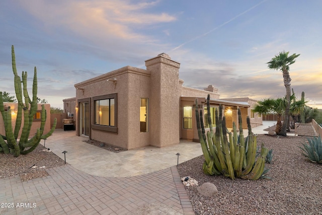 rear view of property with a patio area, fence, and stucco siding