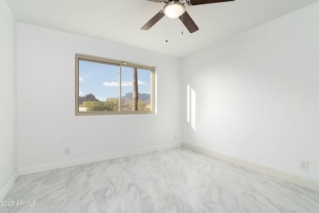 unfurnished room featuring marble finish floor, a ceiling fan, and baseboards