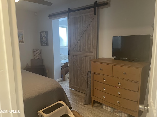 bedroom with light hardwood / wood-style floors and a barn door