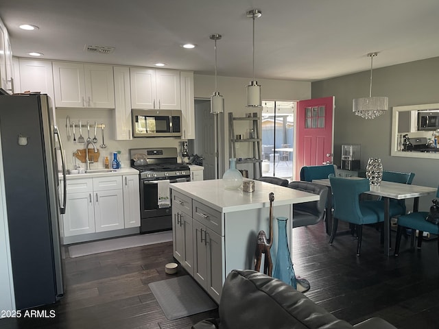 kitchen featuring sink, white cabinetry, hanging light fixtures, dark hardwood / wood-style floors, and stainless steel appliances