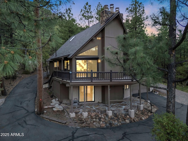 5130 Juniper Loop, Pine, AZ 85544 - view of front facade featuring asphalt driveway, roof with shingles, a chimney, a wooden deck, and a garage