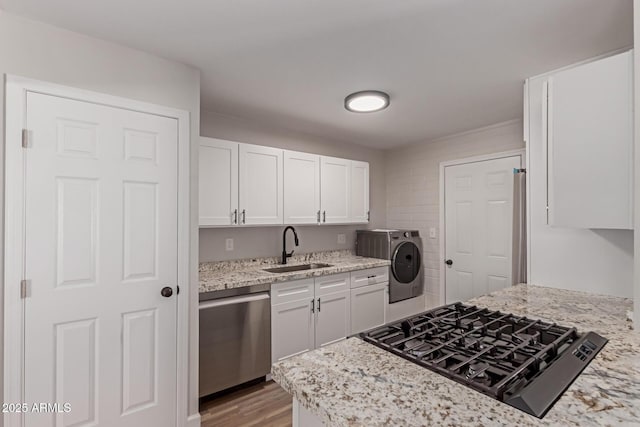 3812 W Seldon Ln, Phoenix, AZ 85051 - kitchen featuring washer / clothes dryer, stainless steel dishwasher, black gas stovetop, white cabinets, and light wood-style flooring