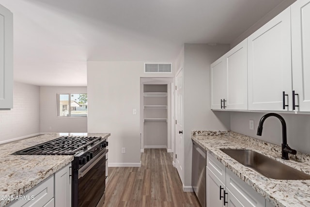 3812 W Seldon Ln, Phoenix, AZ 85051 - kitchen with stainless steel appliances, light wood-style flooring, white cabinetry, and light stone countertops