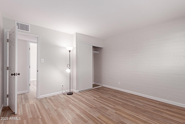 3812 W Seldon Ln, Phoenix, AZ 85051 - unfurnished bedroom with brick wall, light wood finished floors, and a closet