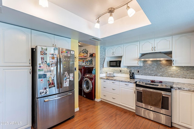 3408 W Carol Ave, Phoenix, AZ 85051 - kitchen featuring washing machine and dryer, under cabinet range hood, white cabinets, light wood finished floors, and appliances with stainless steel finishes