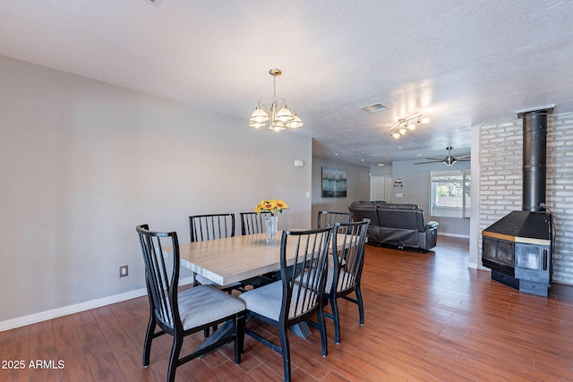 3408 W Carol Ave, Phoenix, AZ 85051 - dining space featuring visible vents, a wood stove, wood finished floors, baseboards, and ceiling fan with notable chandelier