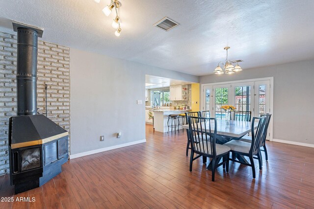 3408 W Carol Ave, Phoenix, AZ 85051 - dining room with a textured ceiling, visible vents, a wood stove, baseboards, and a notable chandelier