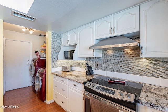 3408 W Carol Ave, Phoenix, AZ 85051 - kitchen with washer and dryer, stainless steel electric range, light wood-type flooring, under cabinet range hood, and visible vents