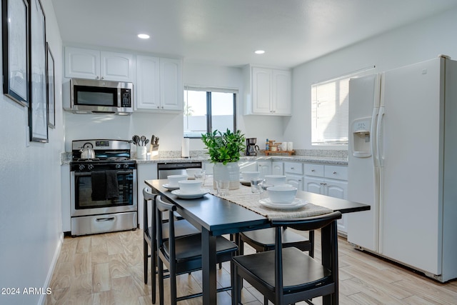 kitchen with white cabinets, stainless steel appliances, light hardwood / wood-style flooring, and a healthy amount of sunlight