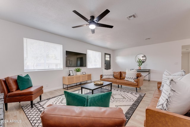 living room with a wealth of natural light, ceiling fan, light hardwood / wood-style floors, and a textured ceiling