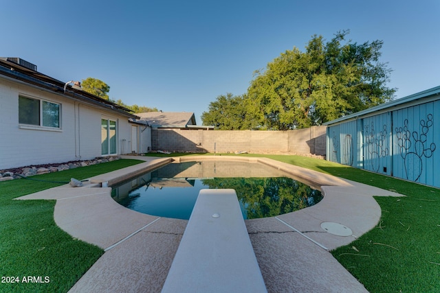 view of pool with a diving board and a yard