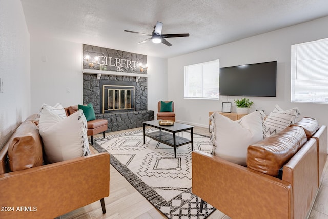 living room with a fireplace, a textured ceiling, plenty of natural light, and ceiling fan