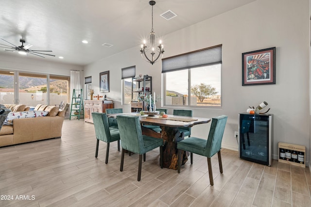 dining space featuring ceiling fan with notable chandelier, light wood-type flooring, and wine cooler