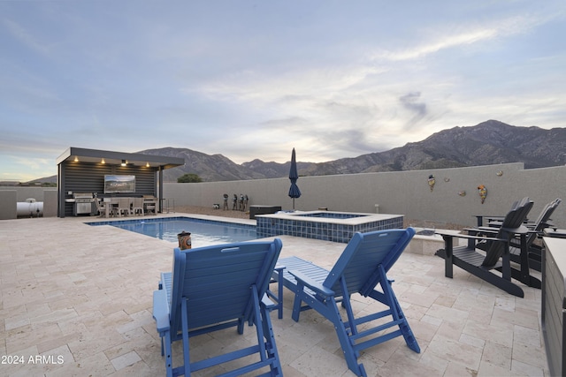 view of pool featuring a mountain view, a patio area, exterior kitchen, and an in ground hot tub