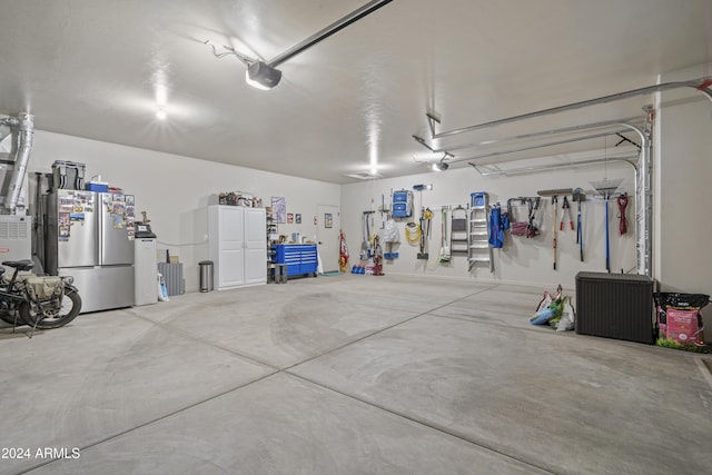 garage with stainless steel fridge and a garage door opener