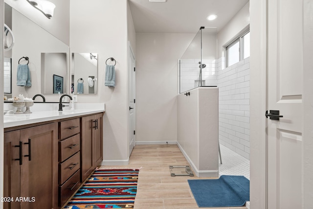 bathroom with a tile shower, vanity, and wood-type flooring