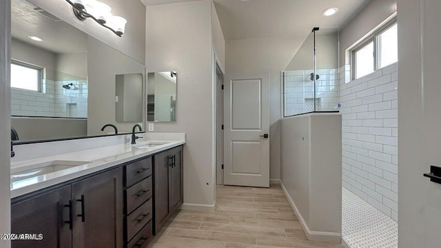 bathroom featuring a tile shower, a wealth of natural light, vanity, and hardwood / wood-style flooring