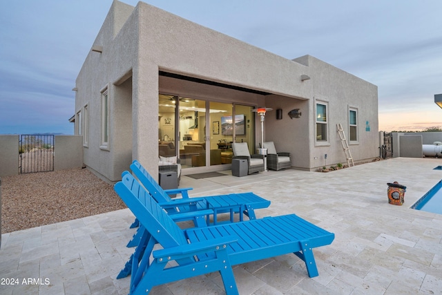 back house at dusk featuring a patio area