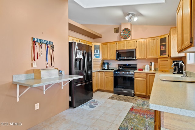 kitchen with lofted ceiling, light tile flooring, appliances with stainless steel finishes, sink, and a breakfast bar area