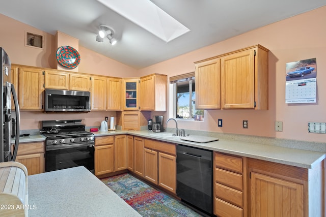 kitchen with light brown cabinets, vaulted ceiling with skylight, gas range, dishwasher, and sink