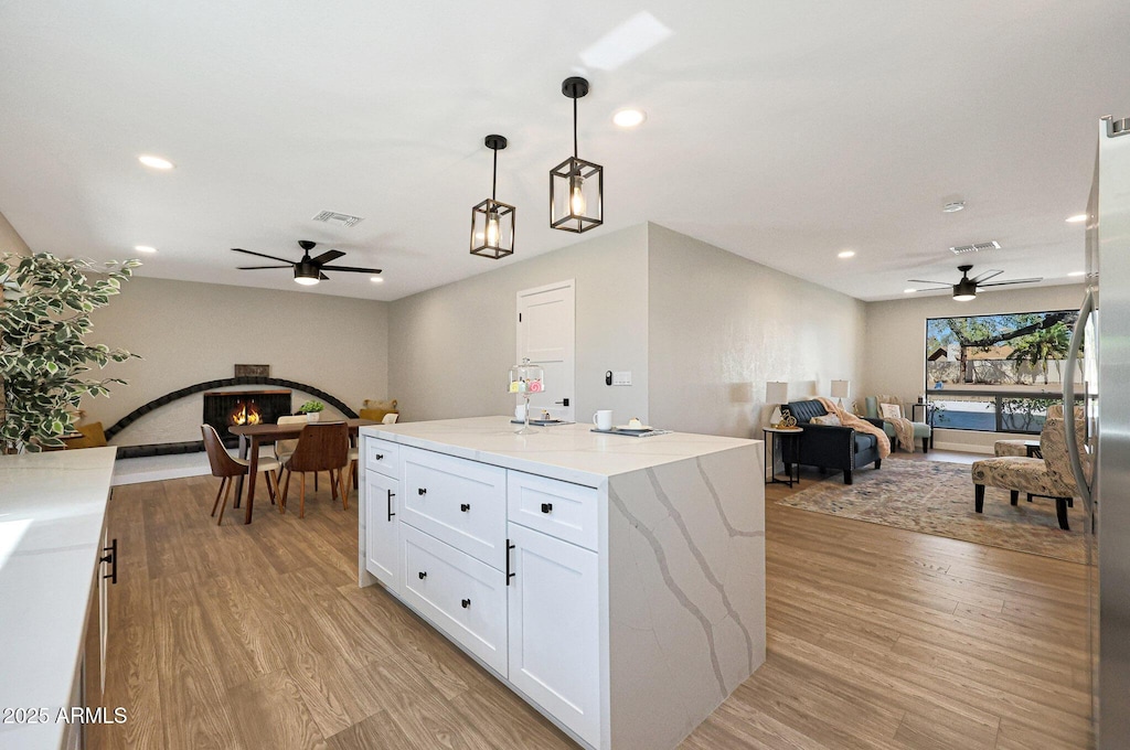 kitchen featuring white cabinets, a center island, pendant lighting, and light hardwood / wood-style floors