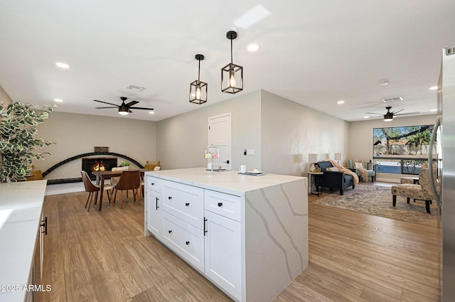 kitchen featuring white cabinets, a center island, pendant lighting, and light hardwood / wood-style floors