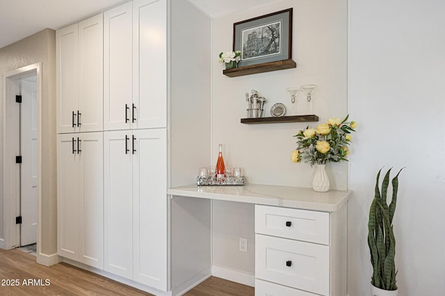 bar featuring light wood-type flooring and white cabinetry