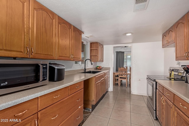 kitchen with visible vents, brown cabinets, a sink, stainless steel appliances, and light tile patterned floors