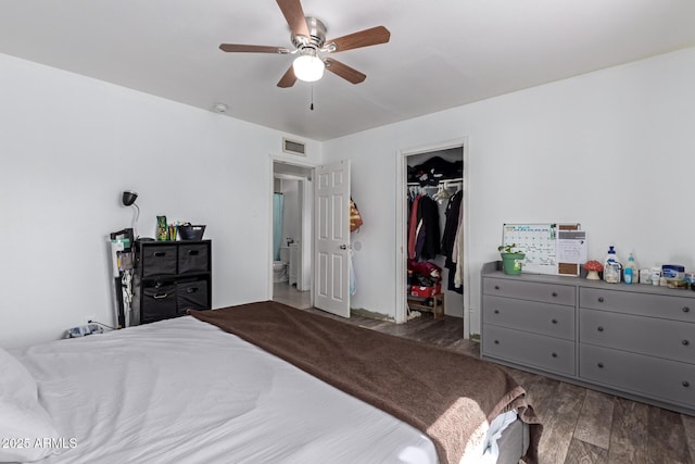 bedroom with visible vents, a walk in closet, wood finished floors, a closet, and ceiling fan