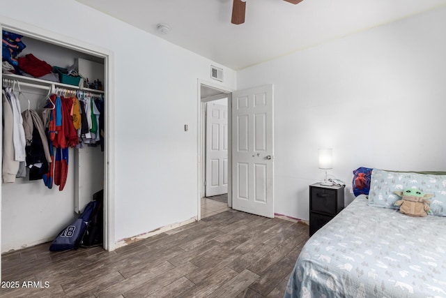 bedroom with a ceiling fan, wood finished floors, visible vents, and a closet