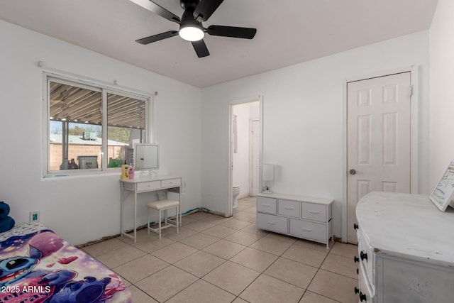 bedroom featuring light tile patterned floors, a ceiling fan, and connected bathroom