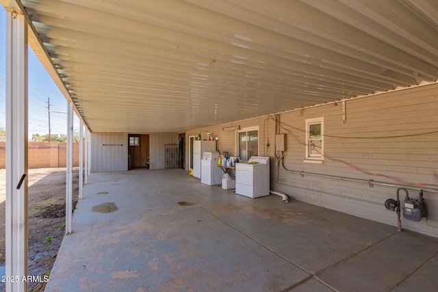 view of patio / terrace with a carport, washing machine and dryer, and fence