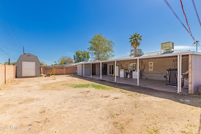 back of house featuring a storage shed, central air condition unit, a fenced backyard, and an outbuilding