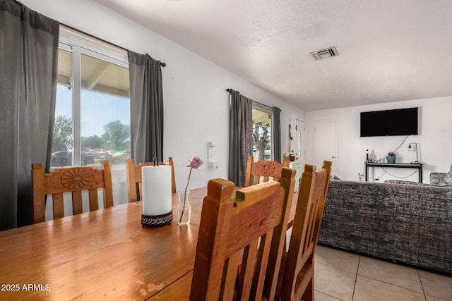 dining space featuring a wealth of natural light, visible vents, a textured ceiling, and light tile patterned floors