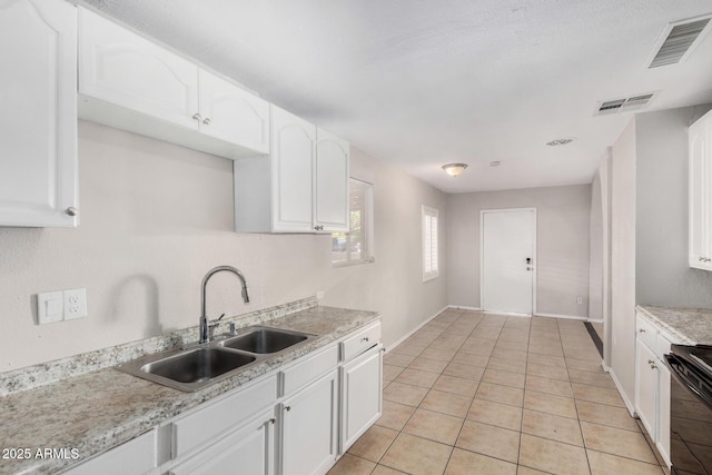 kitchen featuring white cabinetry, black stove, light tile patterned flooring, and sink