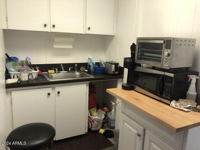 kitchen with white cabinetry, wooden counters, and sink