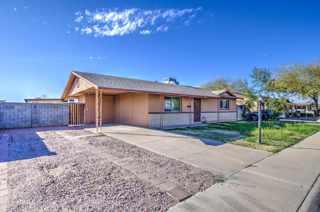 ranch-style home featuring a carport, brick siding, fence, and stucco siding