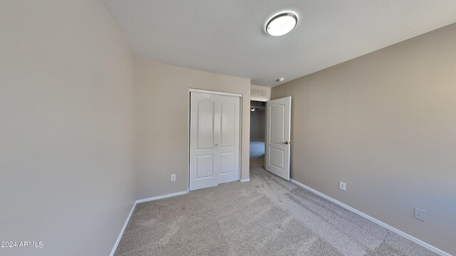 unfurnished bedroom featuring a closet and light colored carpet