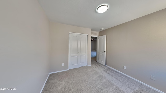 unfurnished bedroom featuring a closet and light carpet