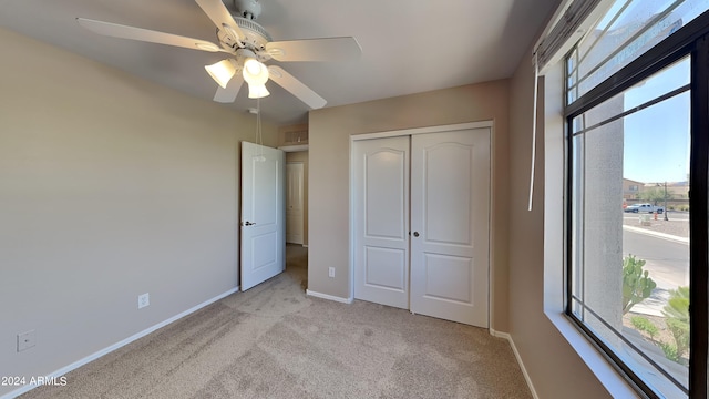 unfurnished bedroom featuring ceiling fan, light carpet, and a closet