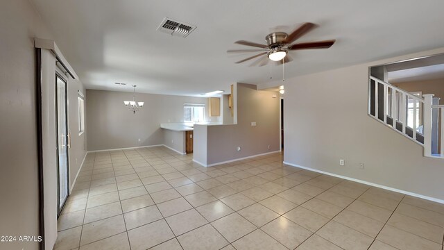 tiled spare room featuring ceiling fan with notable chandelier