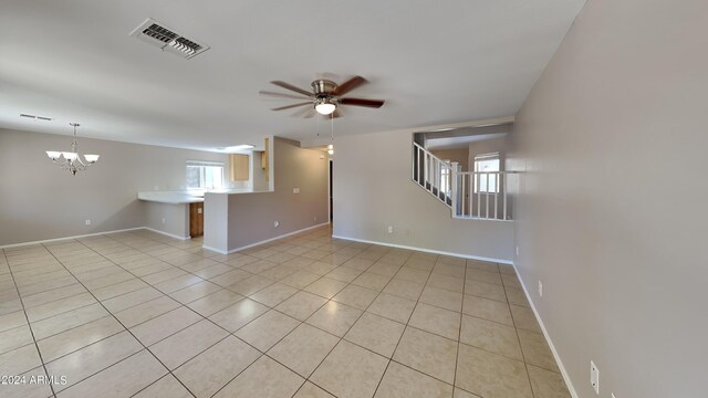 empty room with light tile patterned floors and ceiling fan with notable chandelier