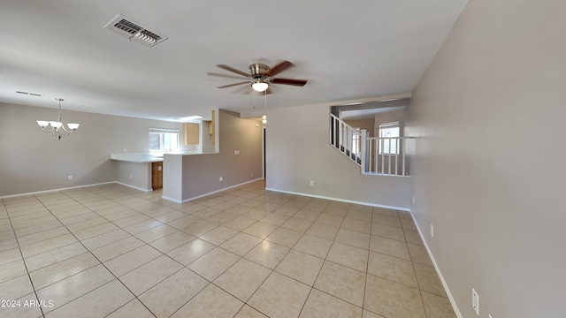 unfurnished living room with plenty of natural light, ceiling fan with notable chandelier, and light tile patterned floors