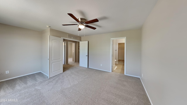 unfurnished bedroom featuring a spacious closet, ceiling fan, light carpet, and a closet