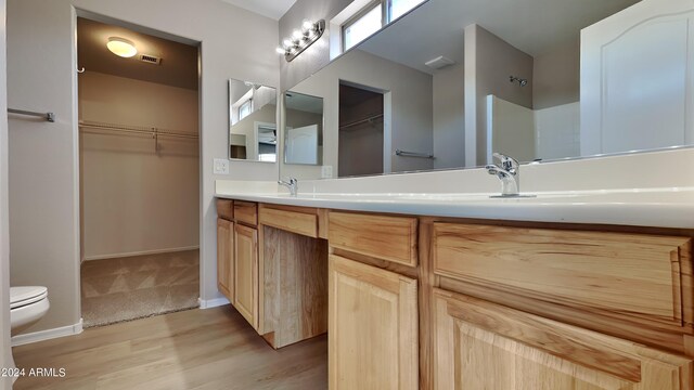 bathroom featuring dual vanity, toilet, and wood-type flooring