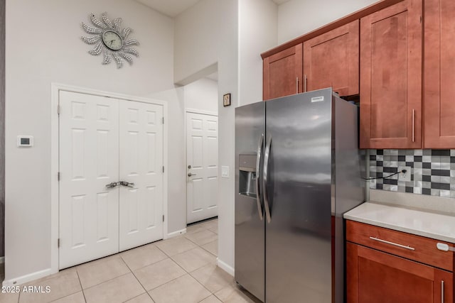 4152 W Bradshaw Creek Ln, New River, AZ 85087 - kitchen with stainless steel fridge, light tile patterned floors, tasteful backsplash, light countertops, and brown cabinetry