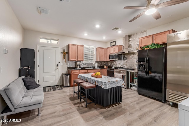 4152 W Bradshaw Creek Ln, New River, AZ 85087 - kitchen featuring black appliances, wall chimney range hood, decorative backsplash, ceiling fan, and light wood-type flooring