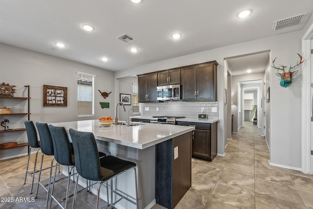 kitchen featuring sink, a center island with sink, dark brown cabinets, and appliances with stainless steel finishes