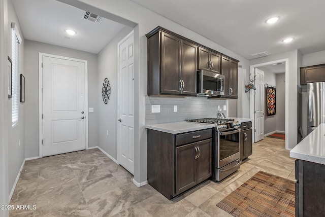 kitchen with dark brown cabinetry, stainless steel appliances, and tasteful backsplash